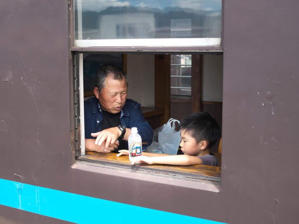 homem e menino na janela do trem